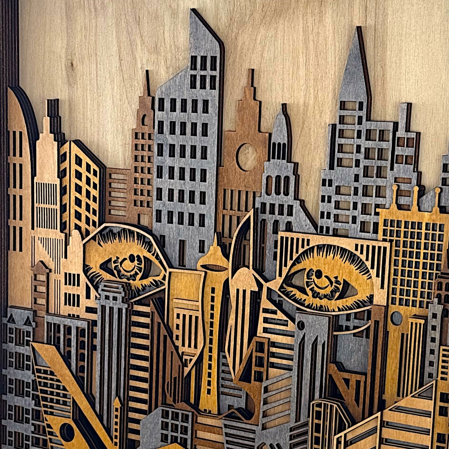 Detail shot of the top portion of wooden wall art featuring laser-cut skyscrapers and expressive carved eyes