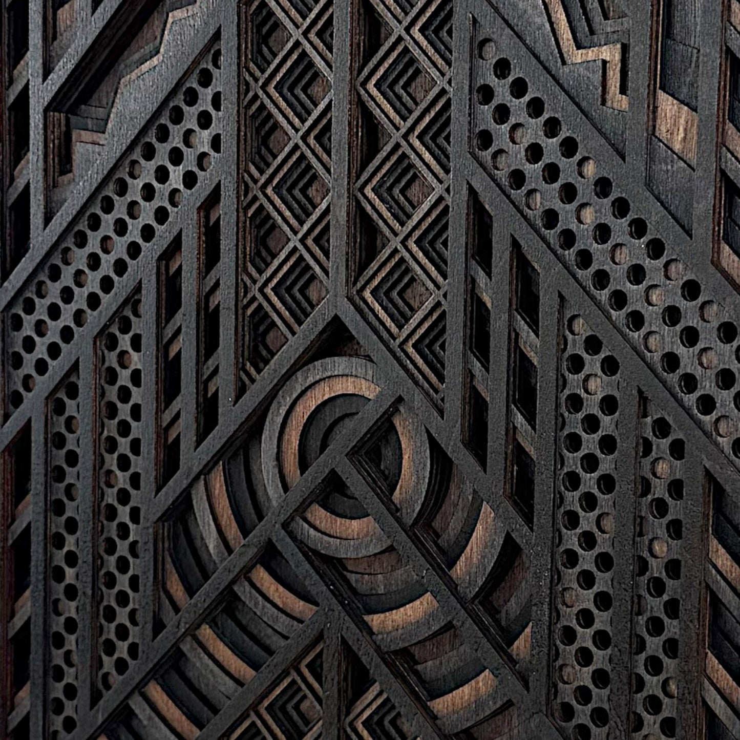 Detailed macro shot of a geometric laser-cut wood artwork, highlighting the layered circular centerpiece, diamond motifs, and perforated accents.