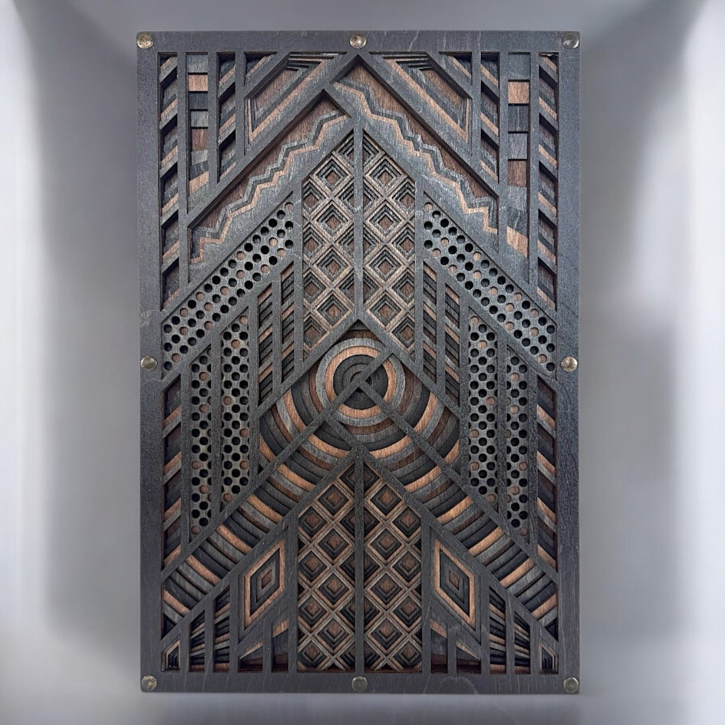 Front-facing view of a six-layer geometric wood wall art piece, showcasing concentric circles, diamond patterns, and perforated textures in black-stained Baltic Birch.