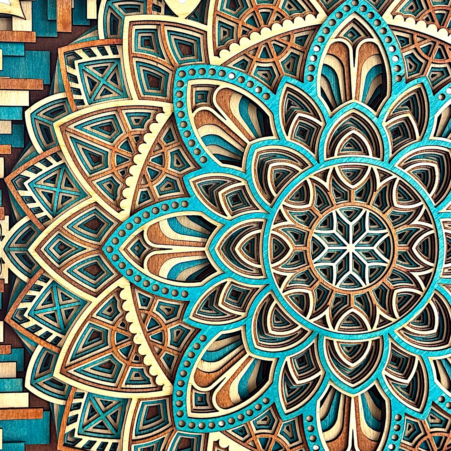 Macro detail of the top left mandala section, showing the precision of the teal dye work, sharp inner cuts, and radial geometry.