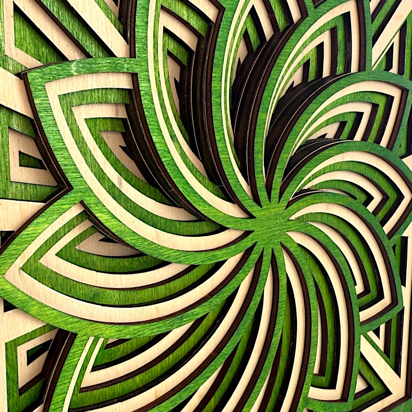 Close-up angle of green and natural birch layers in Floraspiral sculpture, emphasizing curved petal forms and precise cuts.