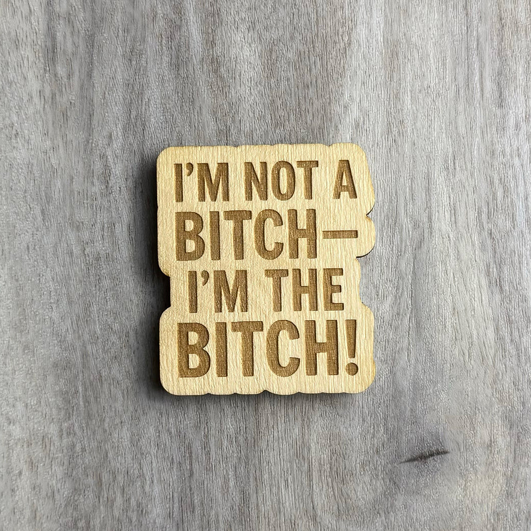 Laser-engraved wooden magnet with the phrase “I’M NOT A BITCH— I’M THE BITCH!” in all capital letters, using bold font. The shape follows the stacked text layout with subtle rounded corners and cutout contours.