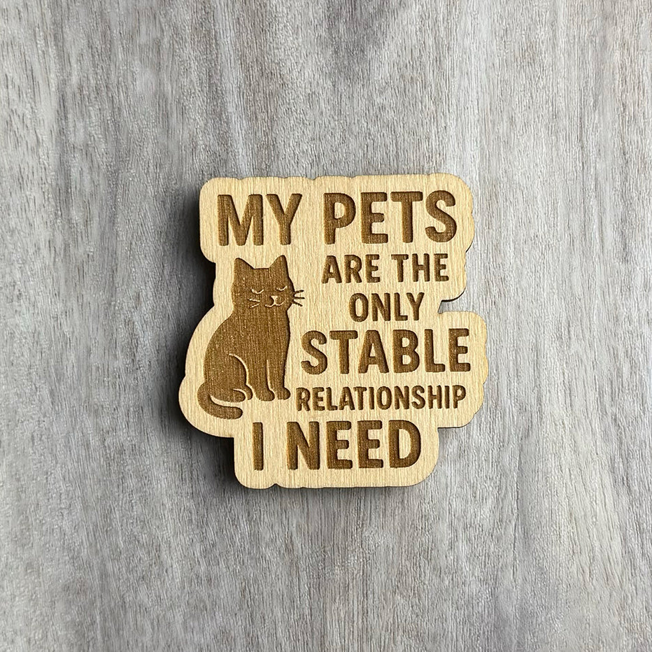 Laser-engraved wooden magnet with the phrase “MY PETS ARE THE ONLY STABLE RELATIONSHIP I NEED.” A calm, content cat is engraved sitting to the left of the text. The shape follows the contours of the cat and the stacked phrase layout.