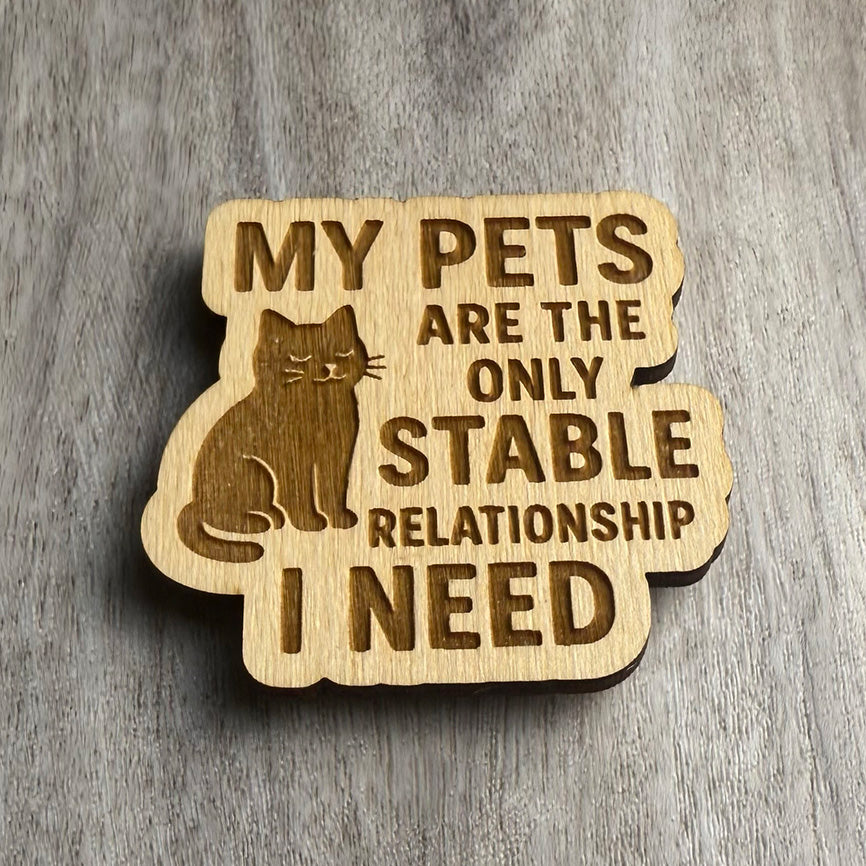 Angled view of the engraved wooden magnet reading “MY PETS ARE THE ONLY STABLE RELATIONSHIP I NEED,” featuring a seated cat with a peaceful expression. Side lighting emphasizes engraving depth and wood texture.