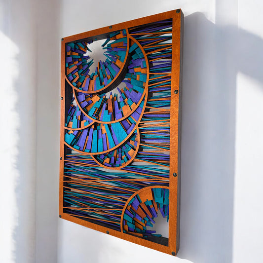 Side-angle view of the wood wall art showing its layered depth and dimensionality, with concentric spiral segments projecting outward in vibrant blue, purple, and orange hues.