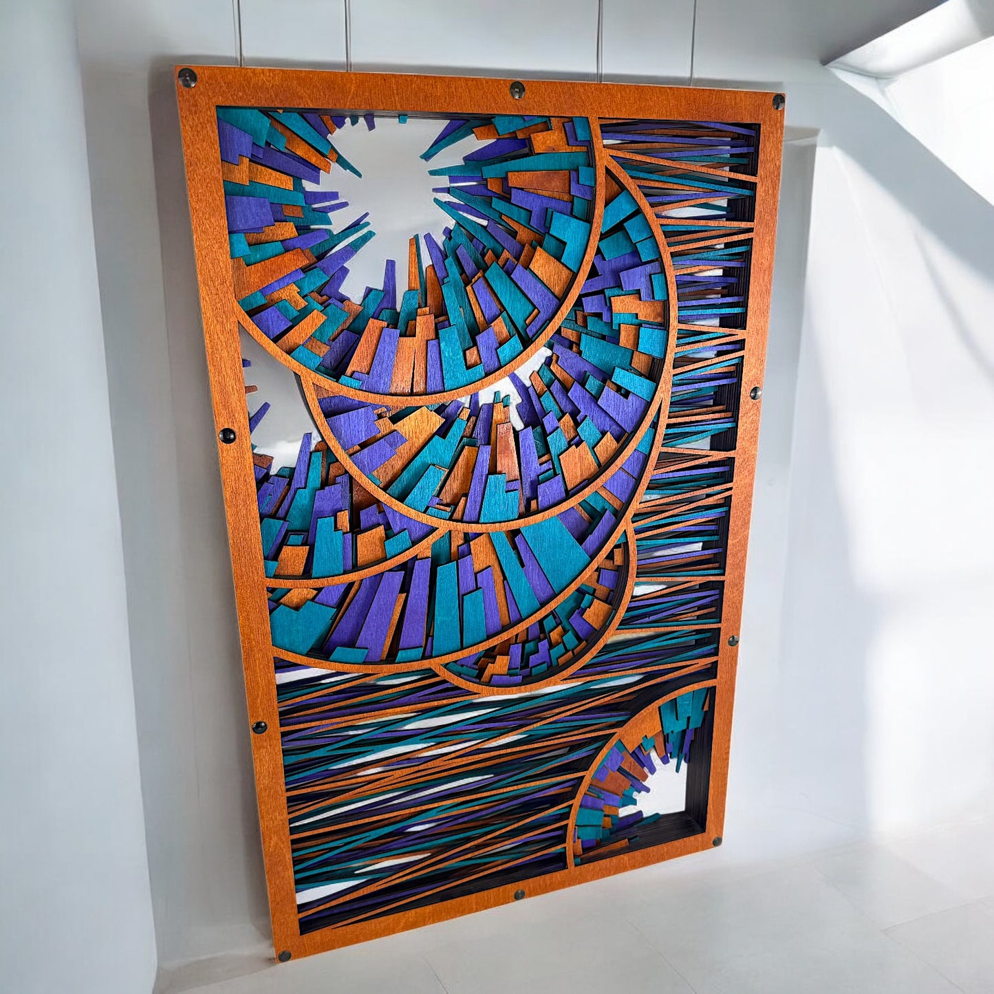 Slightly top-down view of the large wood art piece mounted on a white wall, highlighting its intricate geometric spirals and vibrant stained wood details.