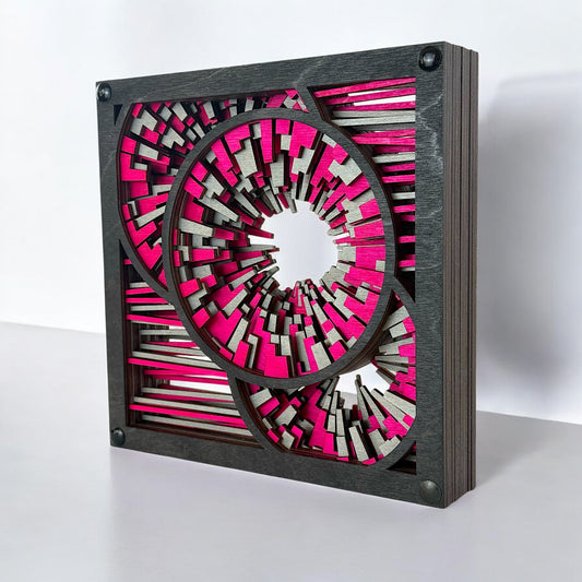 Side angle of the laser-cut Metrorhythm V2 showing layered depth and vibrant contrast in hot pink and silver wood.
