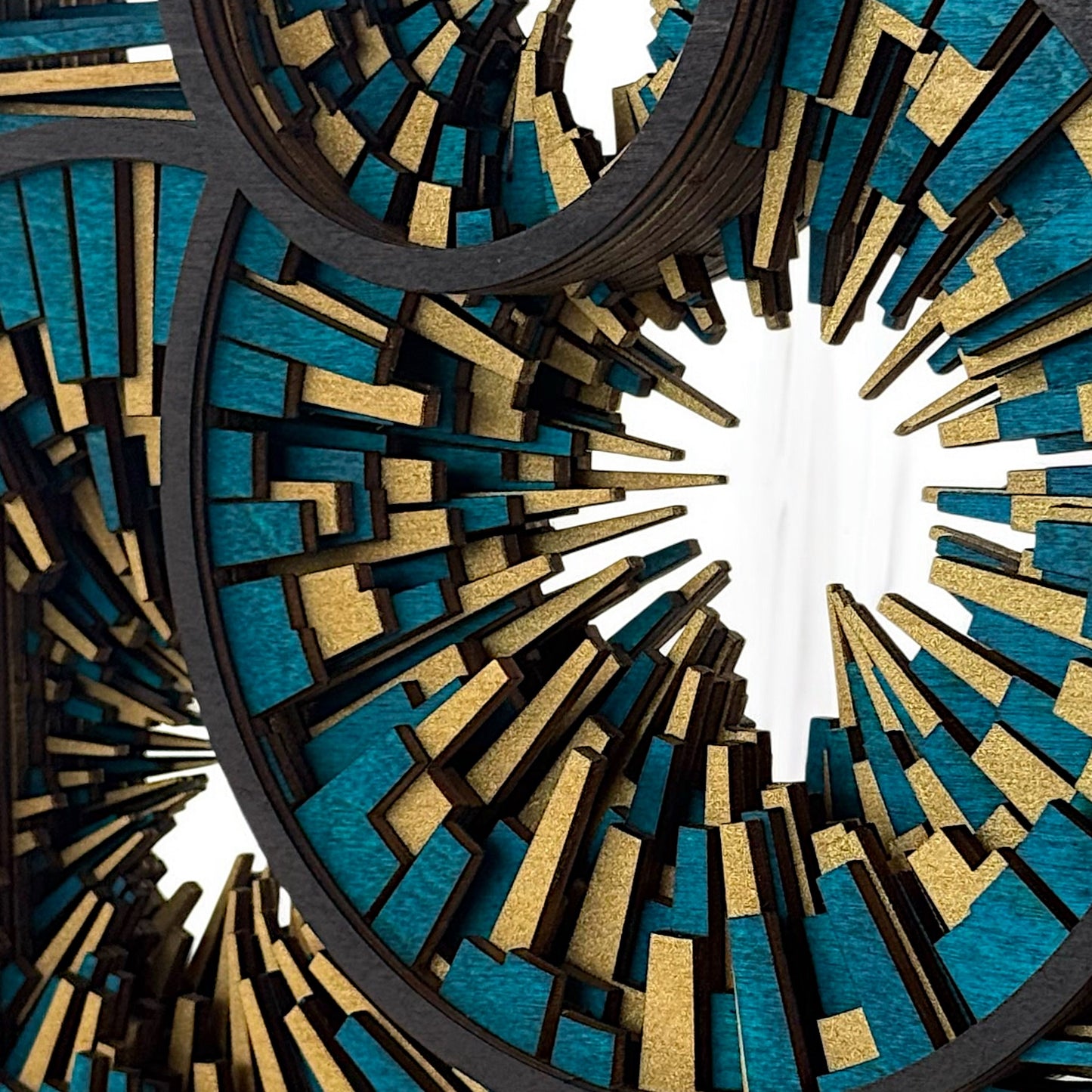 Close-up of layered wood segments in teal and gold, showing fine detail and texture within the radial pattern.