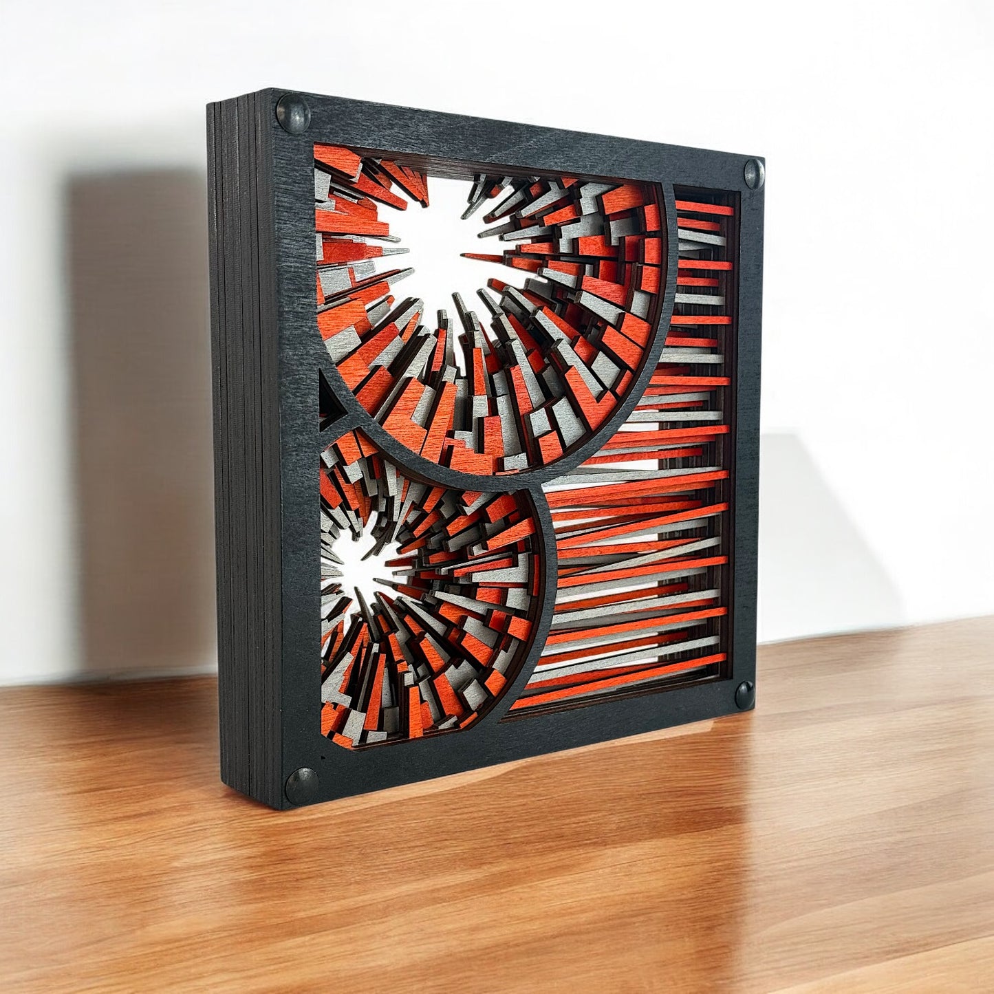 Close-up of geometric laser-cut art on a darker wooden base, emphasizing depth and layered craftsmanship.