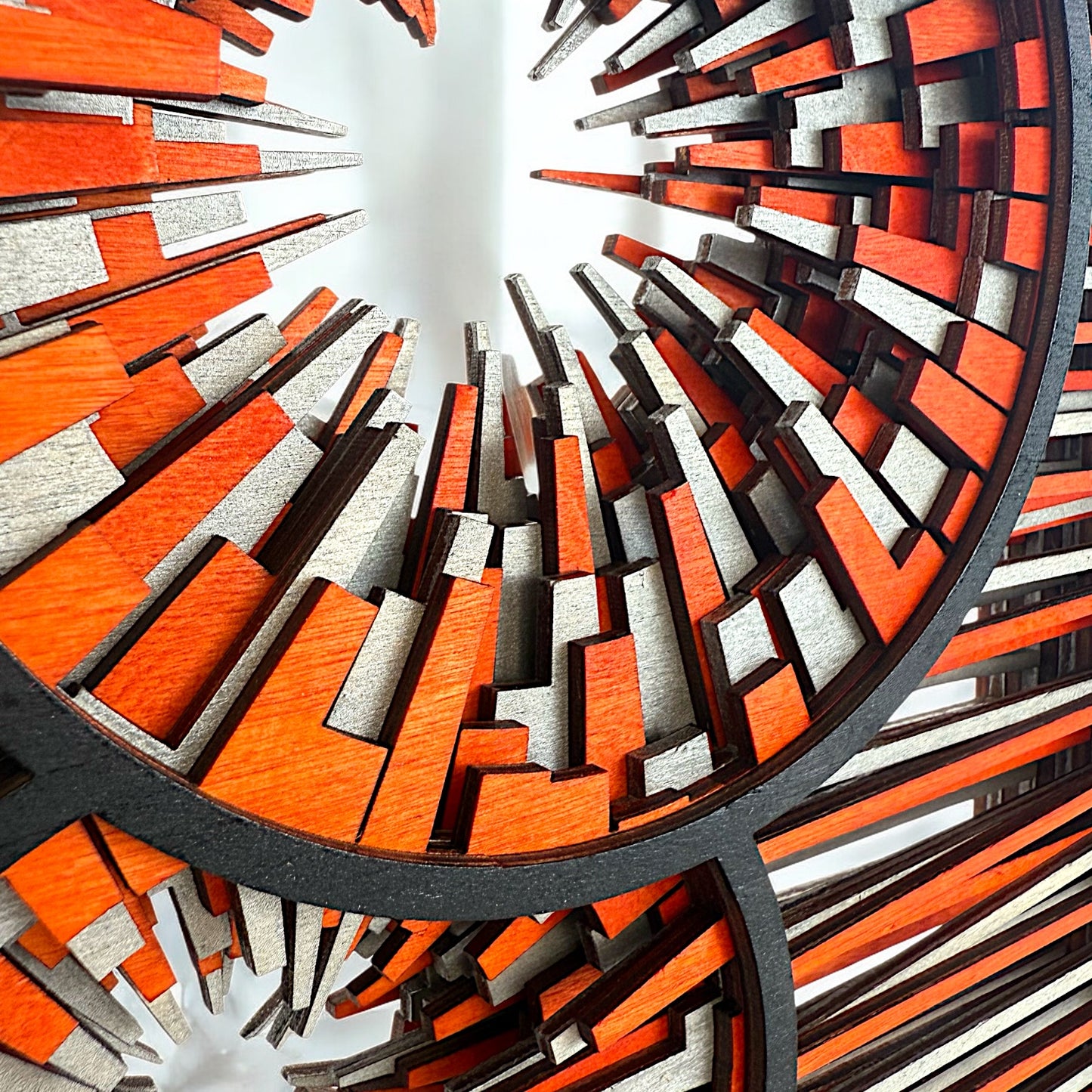 Zoomed-in perspective of the radial elements, revealing crisp edges and color transitions in red and silver wood.