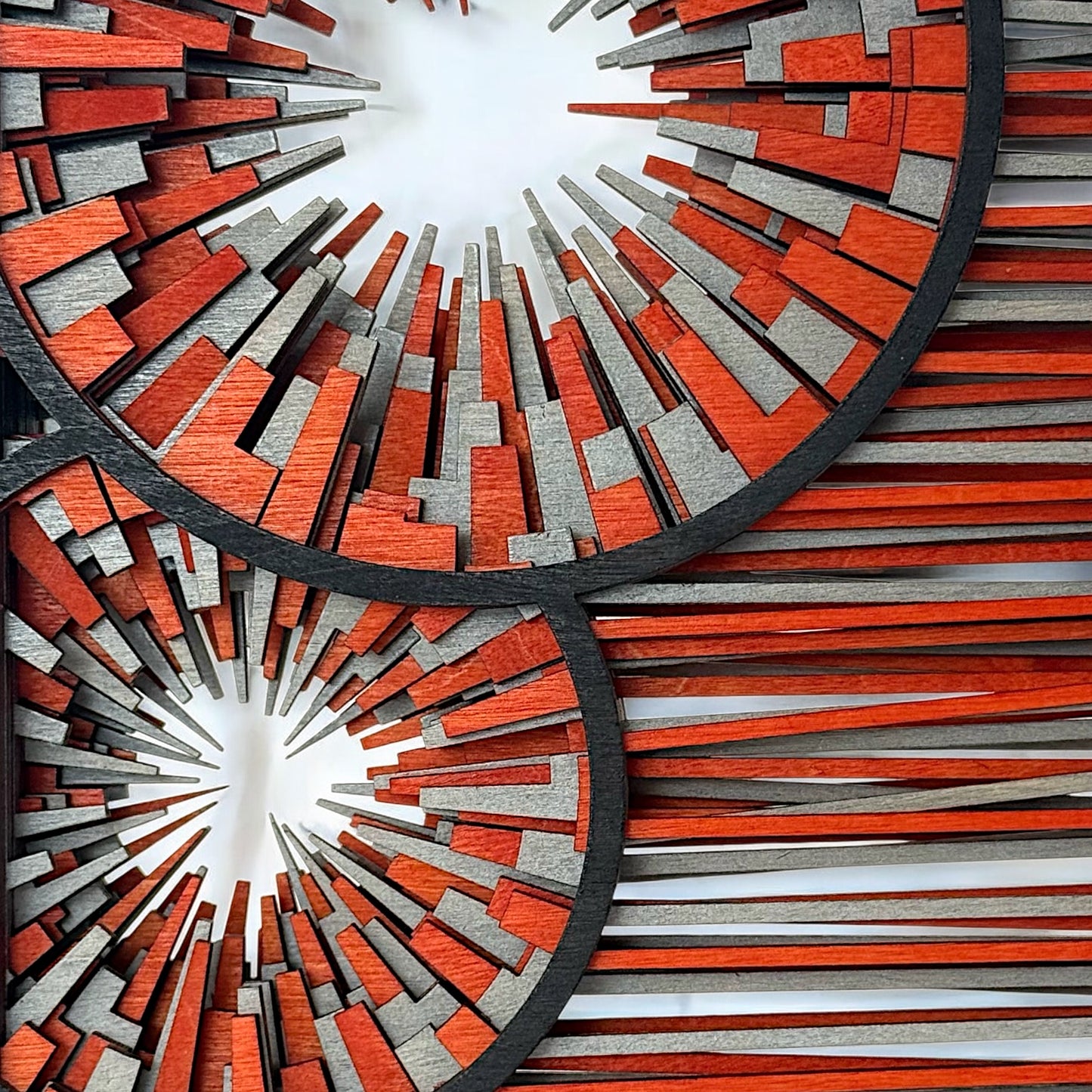 Detailed macro view of the central burst pattern with stacked wooden elements in orange, silver, and black.