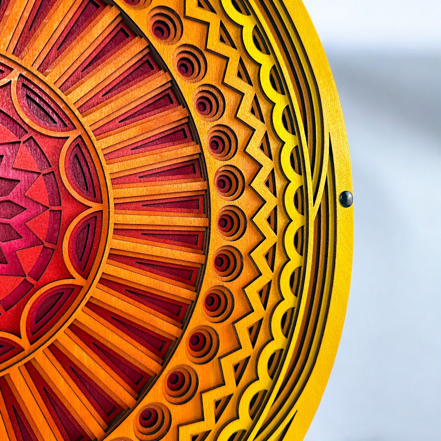 Close-up of the outer edge showing detailed carving and pattern transitions in bright yellow and orange wood layers.