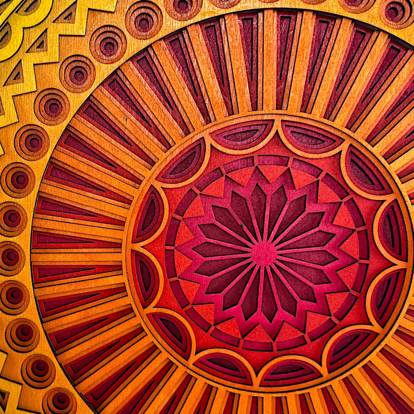 Macro shot of the center of the mandala, emphasizing fine laser-cut details, vibrant red-to-orange gradient, and layered petal-like shapes.