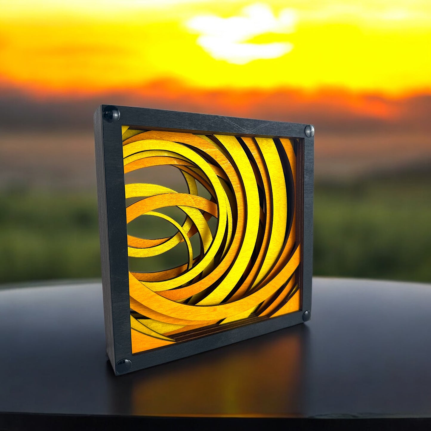 Radiant Drift displayed outdoors with a glowing sunset in the background, enhancing the warm, swirling color palette of the layered design.
