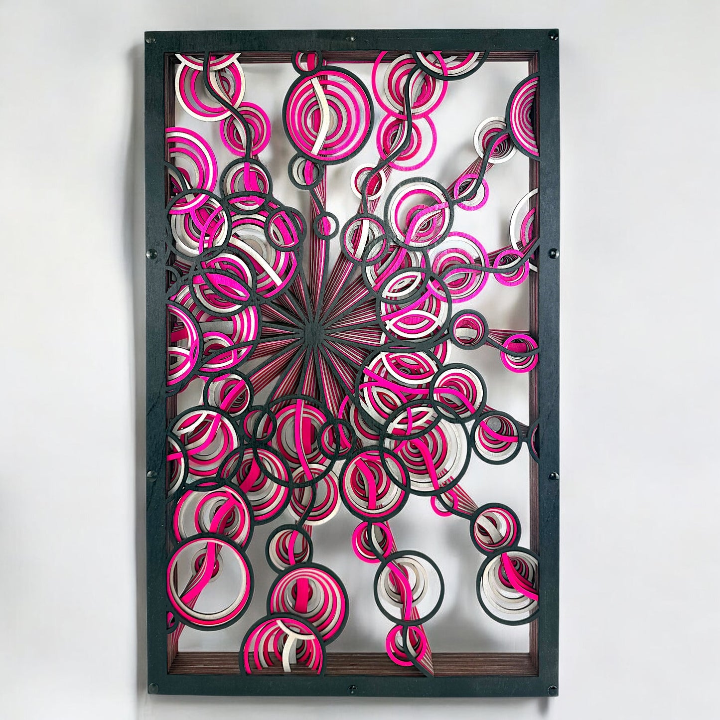 Front view of Sonic Spiral wall art showcasing 12 intricate laser-cut wood layers with swirling, circular geometry in black, magenta, and silver tones.