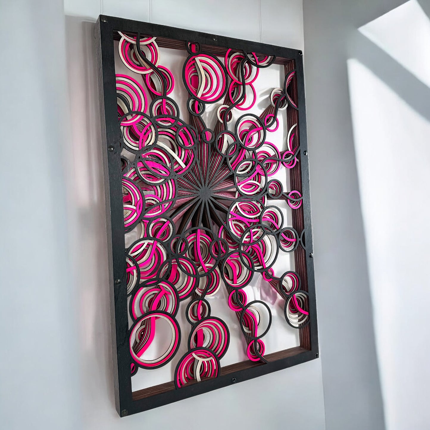 Right-angled hanging display, showing light and shadows interacting with the open layered rings and bold color accents.