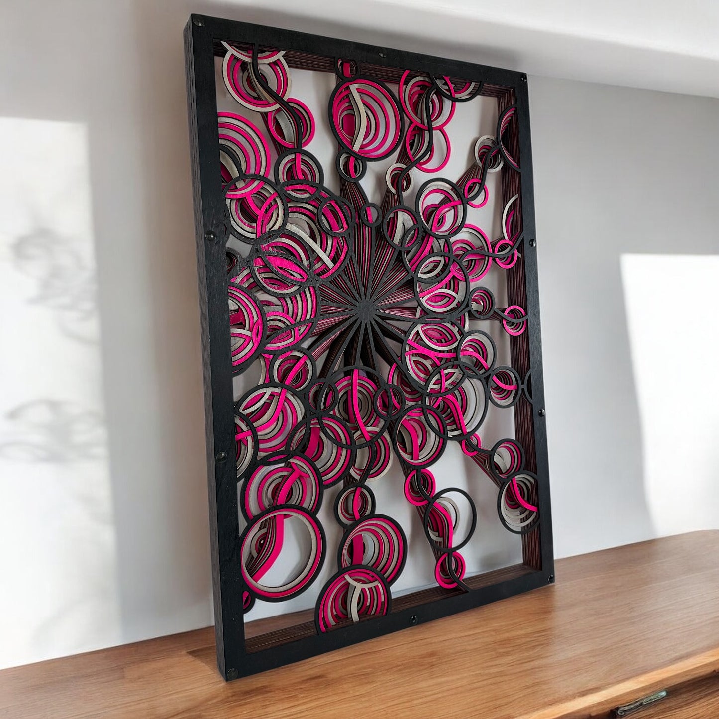 Side-lit view on wooden surface, with spiral shapes casting dynamic shadows, highlighting the radial burst pattern from the center.
