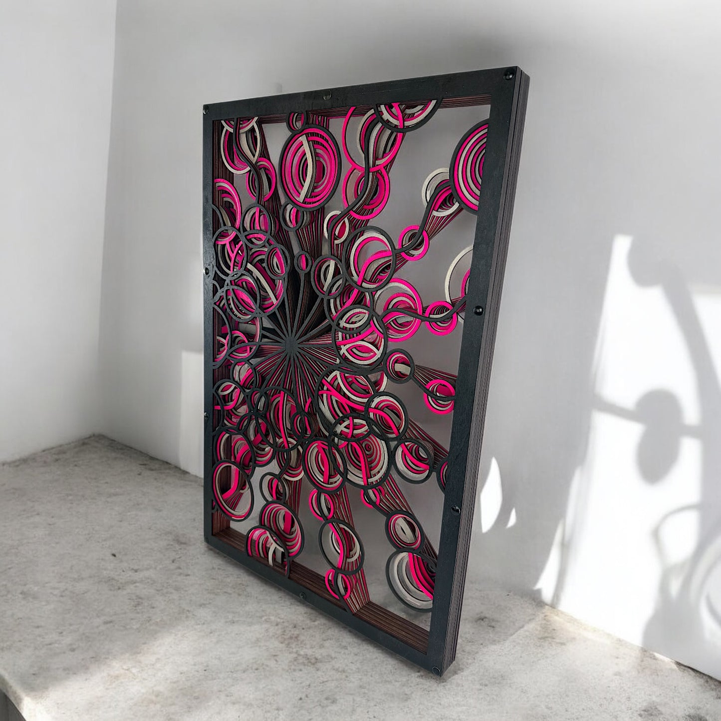 Low side angle with concrete base, capturing how the vibrant cutouts project shadows and depth against the bright wall.