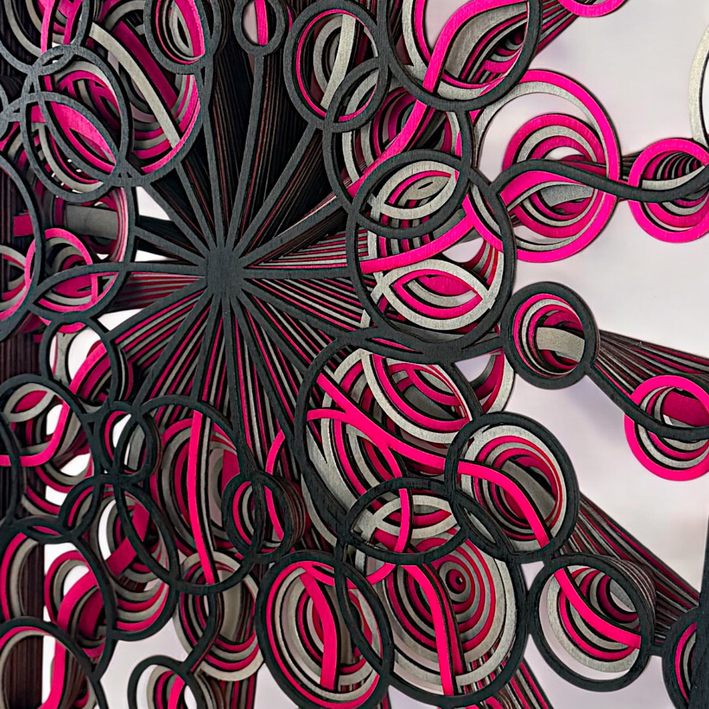 Detail shot of circular patterns, emphasizing the craftsmanship, contrast, and layering of the pink, black, and silver wood pieces.