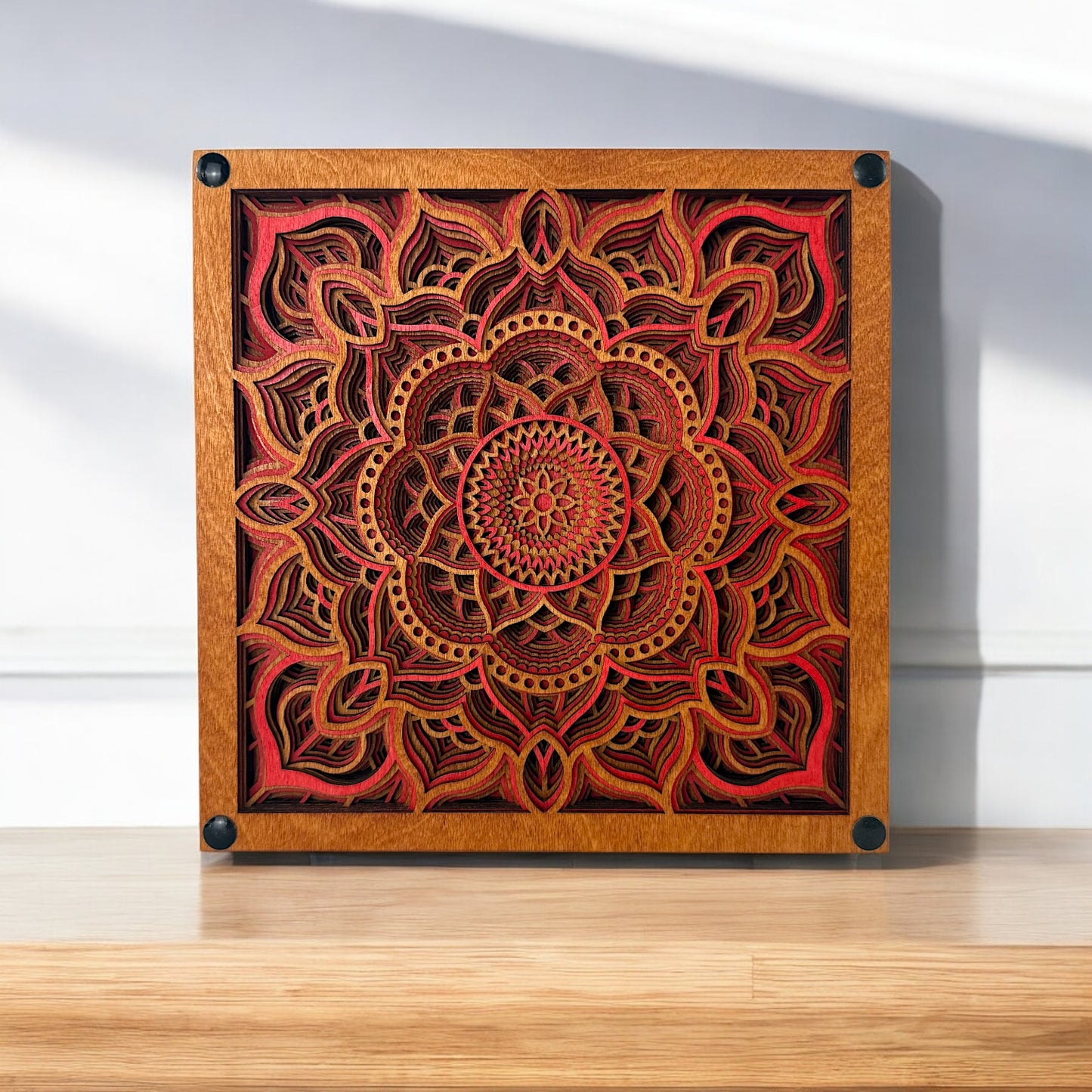 Temple Bloom laser-cut wood art displayed on a wooden surface, highlighting its vibrant red hues and symmetrical mandala form.