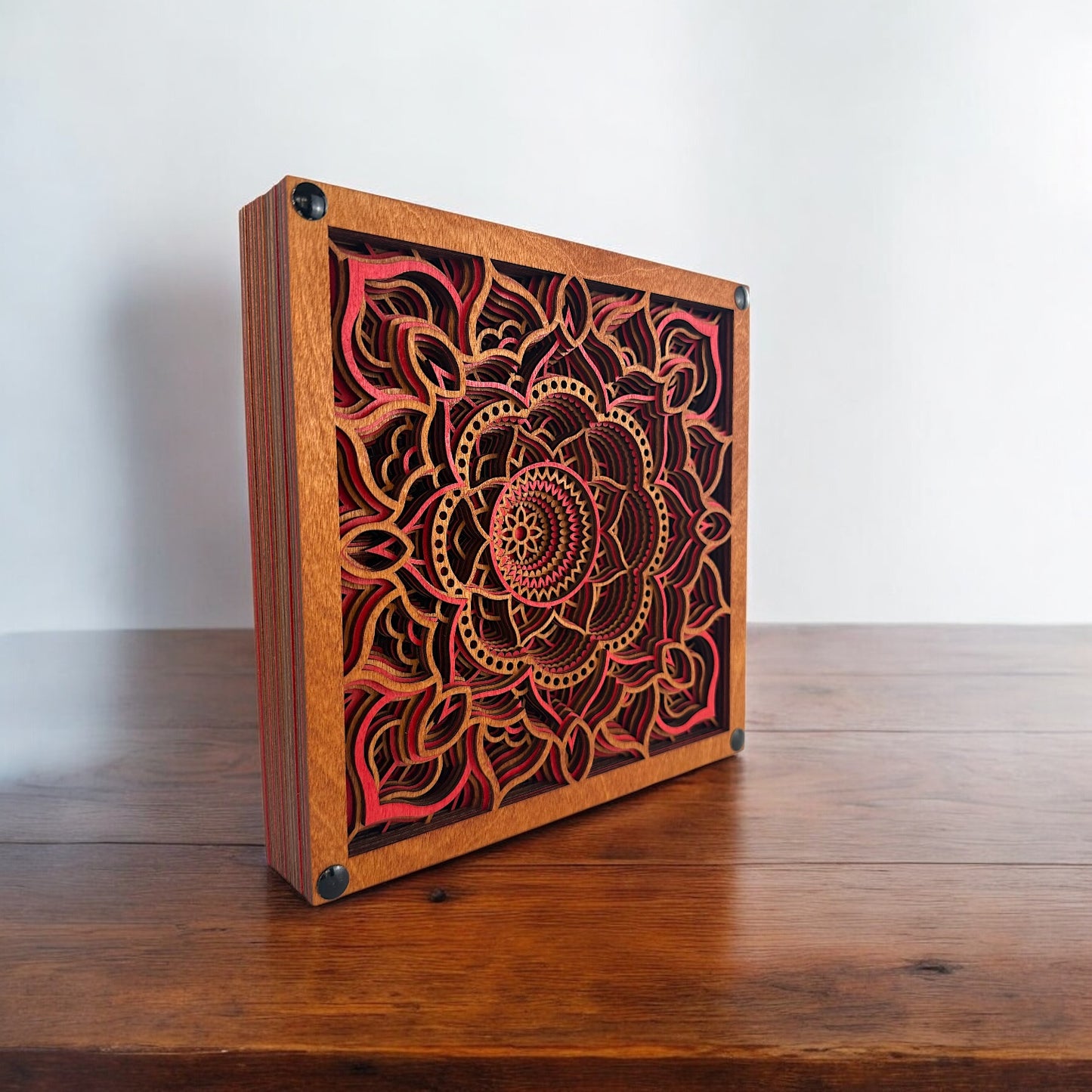 Diagonal view of Temple Bloom layered wood wall art on a rustic table, showing natural grain and hand-dyed detail.