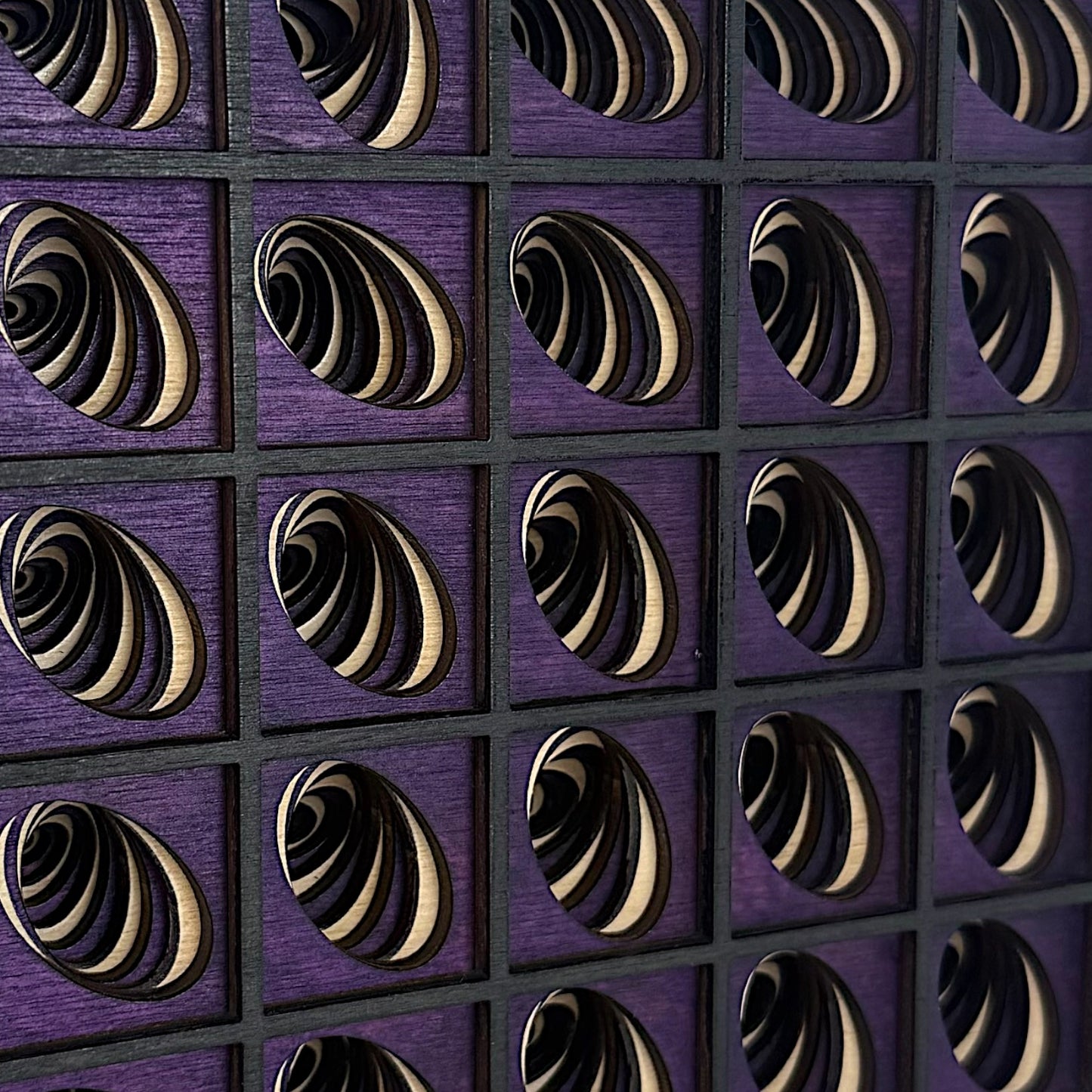 Extreme side angle of Vortex Array art piece emphasizing the depth and curvature of laser-cut elliptical layers in a shadowed grid.