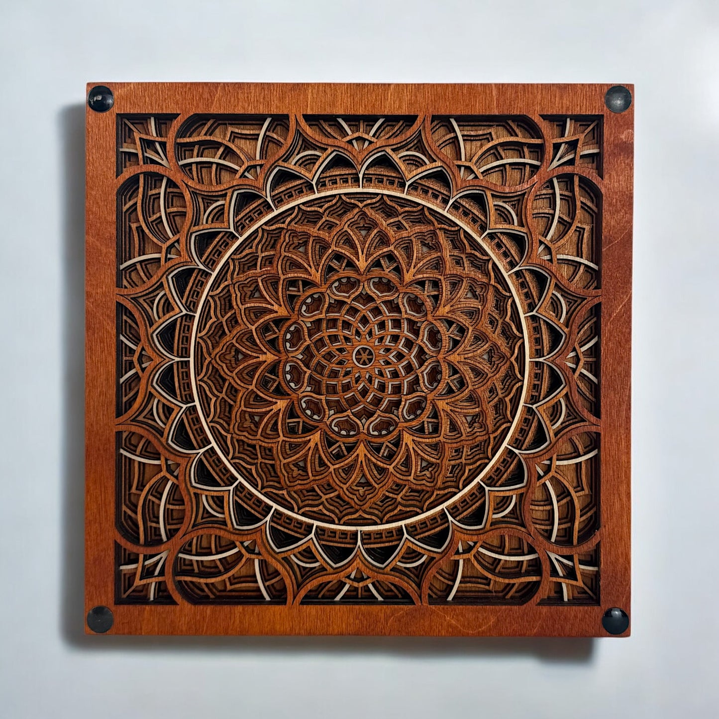 Frontal view of Vortex Reliquary, a 12-layer laser-cut wood mandala in rich walnut tones with geometric detailing.