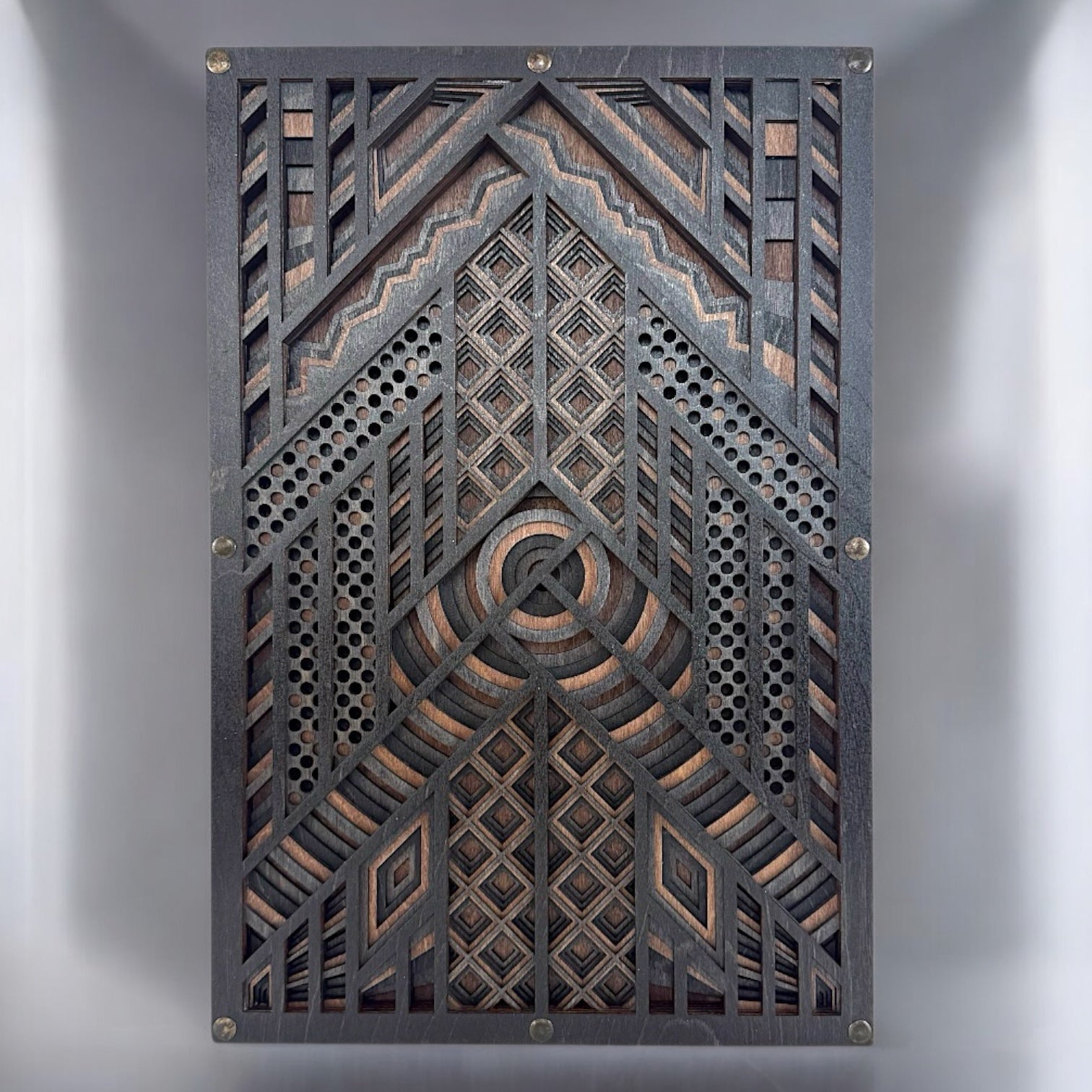 Front-facing view of a six-layer geometric wood wall art piece, showcasing concentric circles, diamond patterns, and perforated textures in black-stained Baltic Birch.