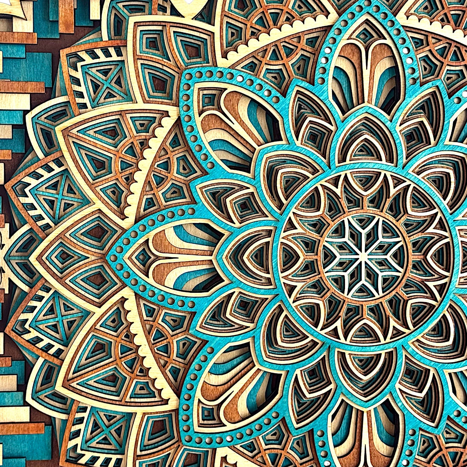 Macro detail of the top left mandala section, showing the precision of the teal dye work, sharp inner cuts, and radial geometry.