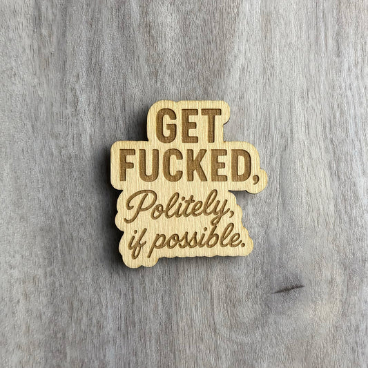 Laser-cut wooden magnet engraved with the phrase Get Fucked, Politely, if possible, using a combination of bold block lettering and cursive script, displayed on a gray wood background.