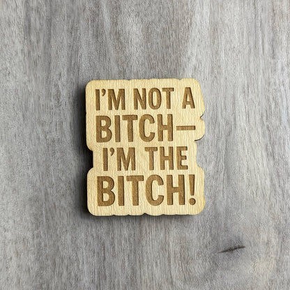 Laser-engraved wooden magnet with the phrase “I’M NOT A BITCH— I’M THE BITCH!” in all capital letters, using bold font. The shape follows the stacked text layout with subtle rounded corners and cutout contours.