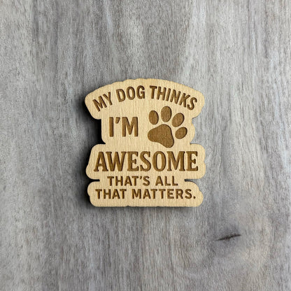 Laser-engraved wooden magnet with the phrase “MY DOG THINKS I’M AWESOME THAT’S ALL THAT MATTERS.” A paw print icon is engraved between the words “I’M” and “AWESOME.” The magnet has a stacked, curved shape with rounded, flowing edges.
