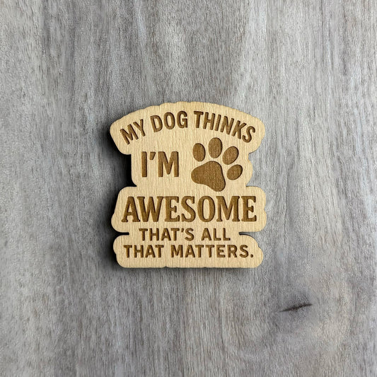 Laser-engraved wooden magnet with the phrase “MY DOG THINKS I’M AWESOME THAT’S ALL THAT MATTERS.” A paw print icon is engraved between the words “I’M” and “AWESOME.” The magnet has a stacked, curved shape with rounded, flowing edges.