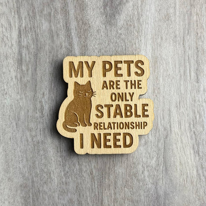 Laser-engraved wooden magnet with the phrase “MY PETS ARE THE ONLY STABLE RELATIONSHIP I NEED.” A calm, content cat is engraved sitting to the left of the text. The shape follows the contours of the cat and the stacked phrase layout.