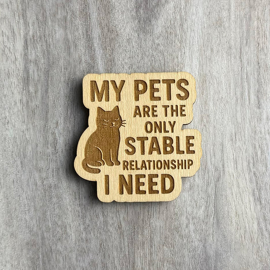 Laser-engraved wooden magnet with the phrase “MY PETS ARE THE ONLY STABLE RELATIONSHIP I NEED.” A calm, content cat is engraved sitting to the left of the text. The shape follows the contours of the cat and the stacked phrase layout.