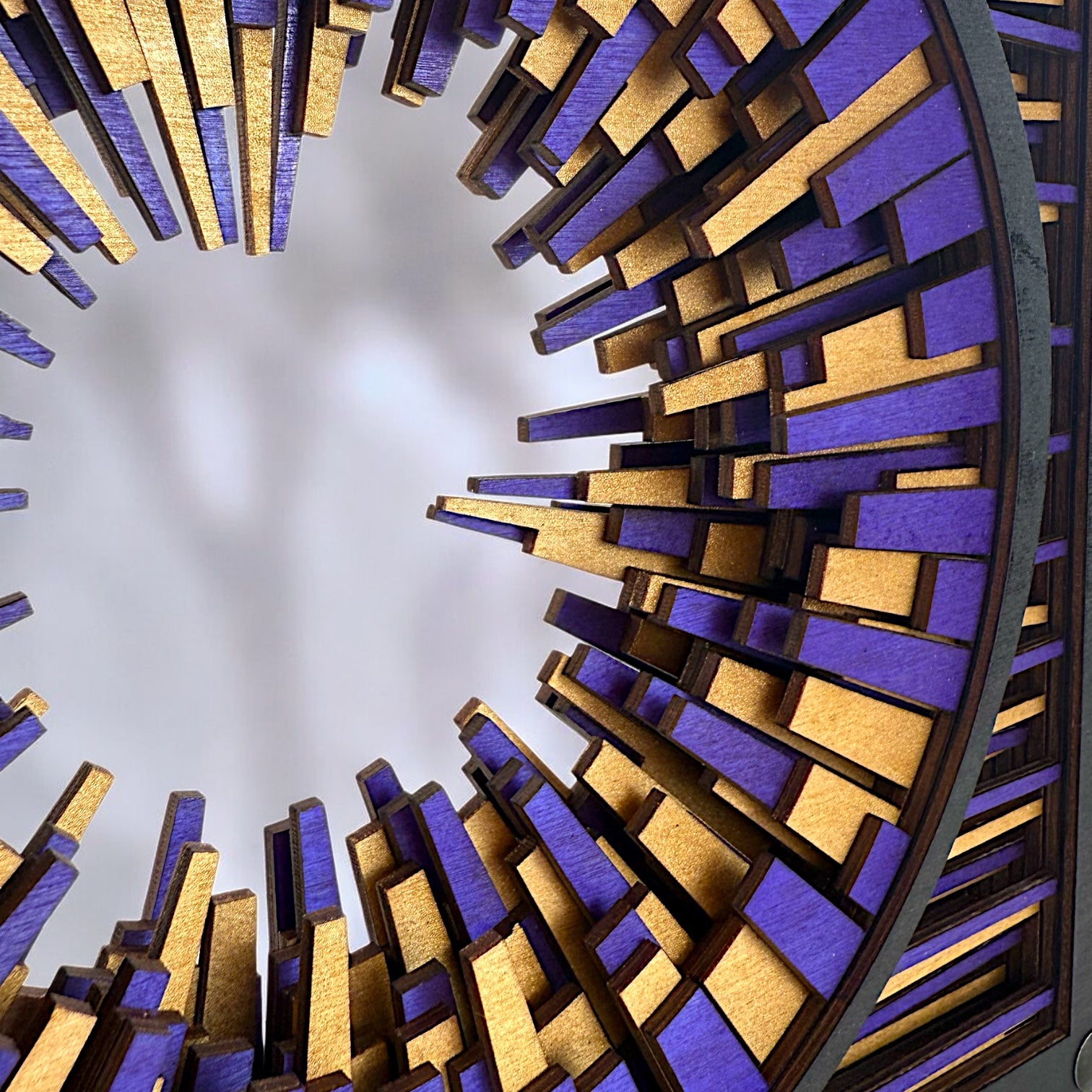 Macro detail of laser-cut birch layers in Metrorhythm V1, revealing intricate interlocking shapes and vibrant hand-dyed color.
