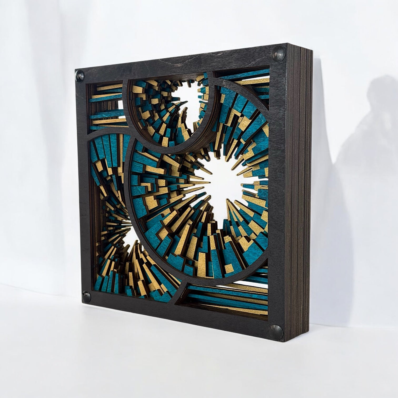 Freestanding wood sculpture viewed from the right side, showing stacked birch layers with vivid turquoise and shimmering gold.