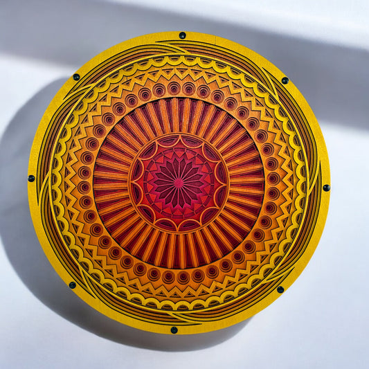 Top-down view of a vibrant, circular 9-layer laser-cut wood mandala featuring yellow, orange, and red hues with intricate geometric patterns.