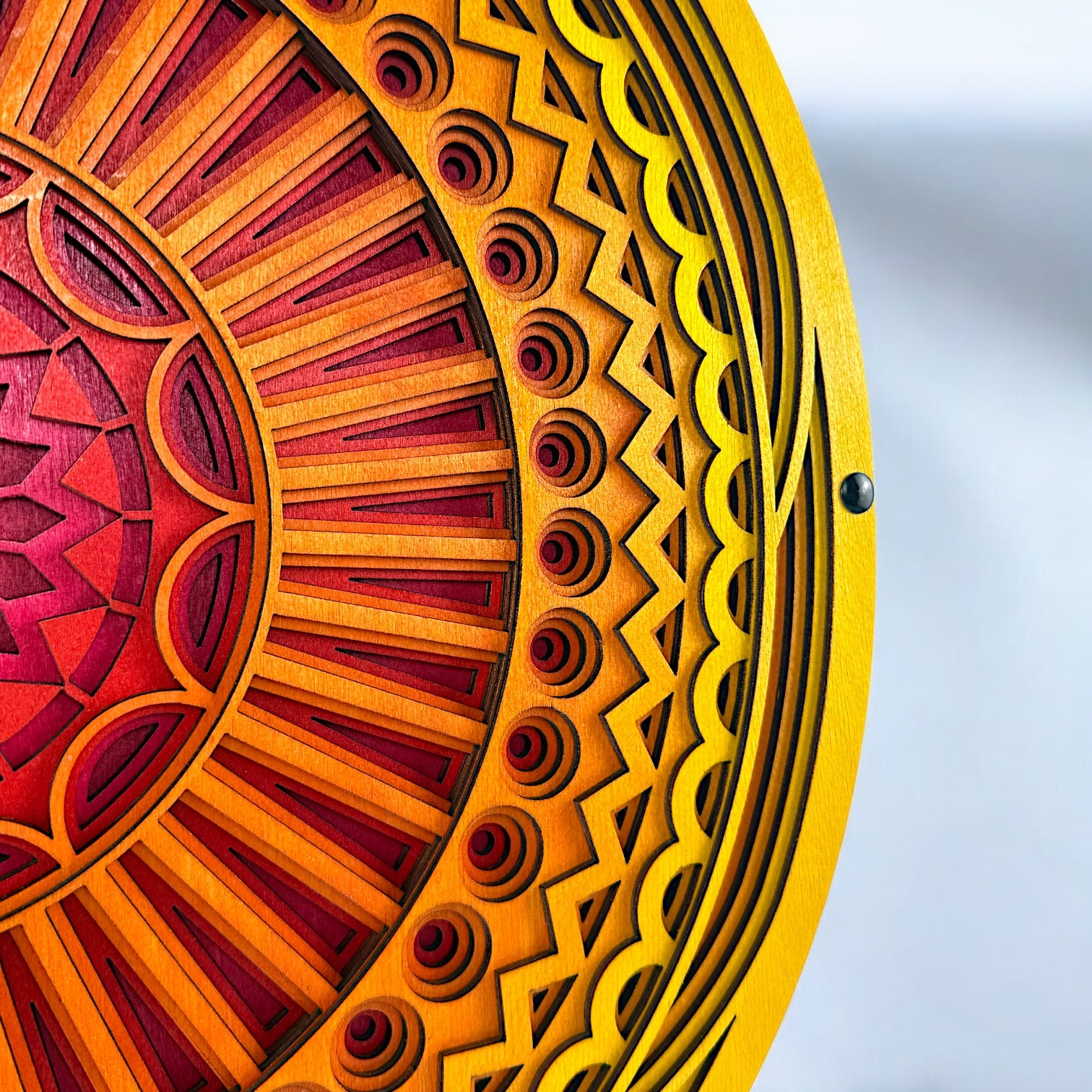 Close-up of the outer edge showing detailed carving and pattern transitions in bright yellow and orange wood layers.