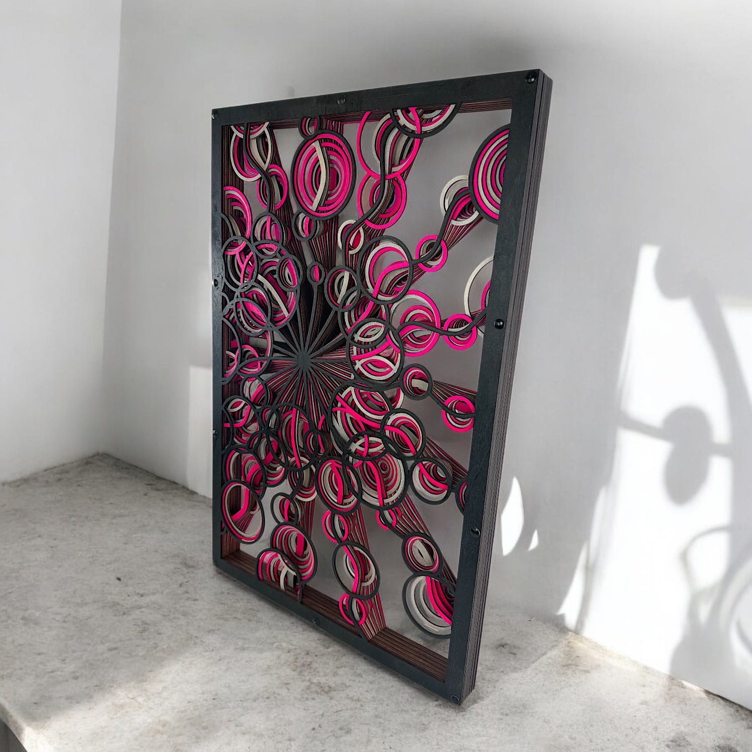 Low side angle with concrete base, capturing how the vibrant cutouts project shadows and depth against the bright wall.