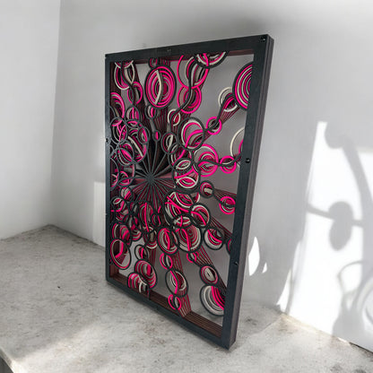 Low side angle with concrete base, capturing how the vibrant cutouts project shadows and depth against the bright wall.
