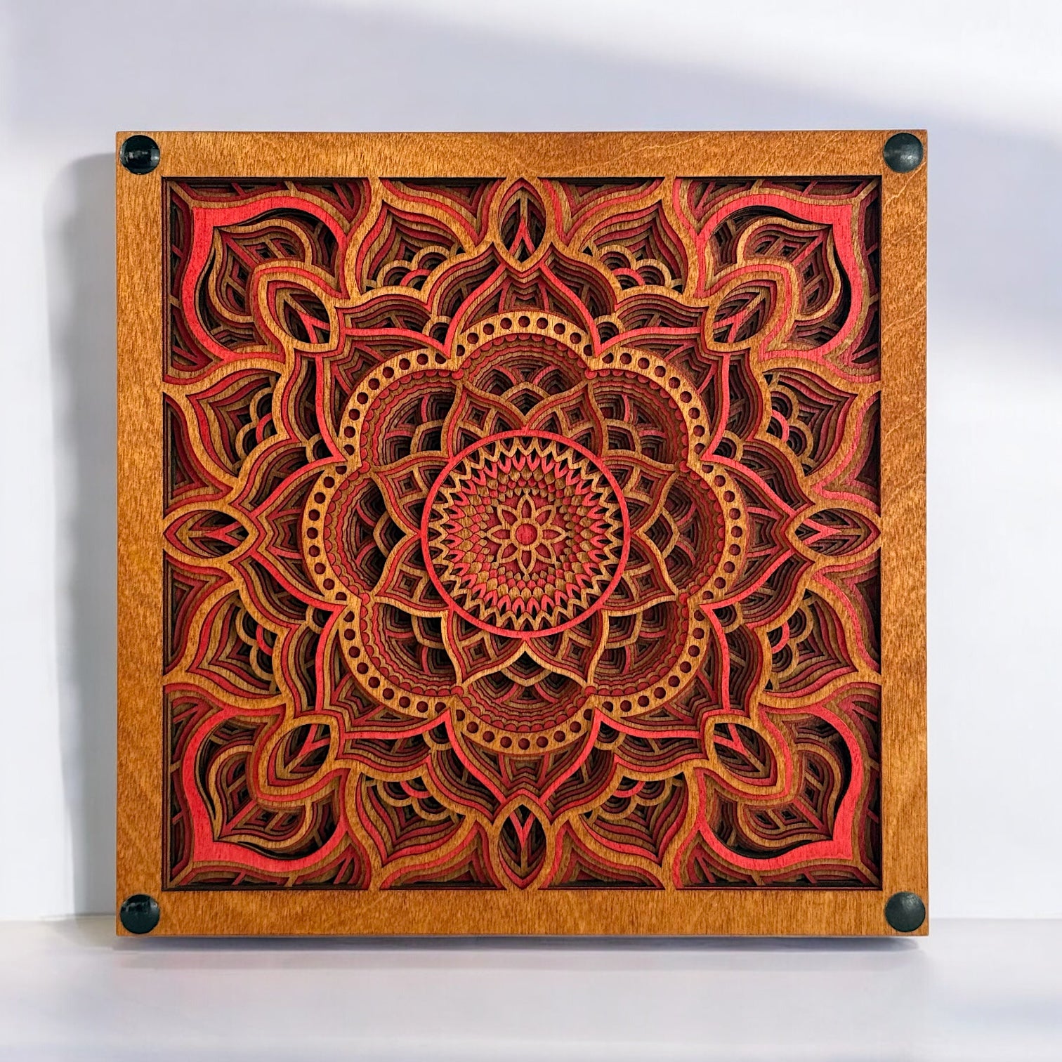 Front-facing view of Temple Bloom laser-cut wood art, showcasing intricate 12-layer mandala design in warm red, gold, and brown tones.