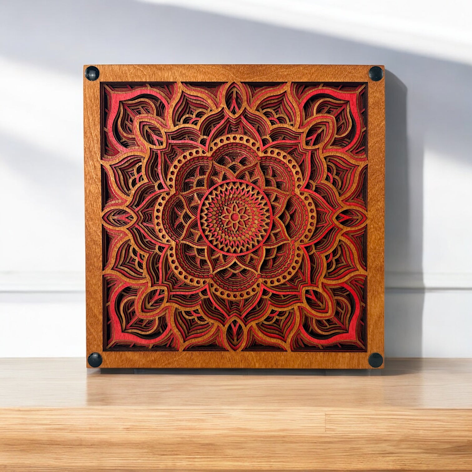 Temple Bloom laser-cut wood art displayed on a wooden surface, highlighting its vibrant red hues and symmetrical mandala form.